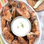 Dill pickle wings in a white bowl with dipping sauce