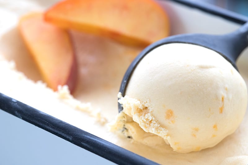 Close up shot of homemade peach ice cream being scooped out of a container