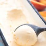 Titled Pinterest image of an ice cream scoop scooping keto peach ice cream out of a metal tub.