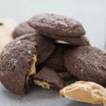A stack of keto chocolate peanut butter cookies with a scoop of peanut butter in front