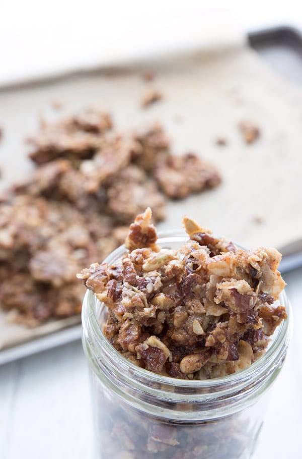 A glass jar full of keto granola clusters with the pan in the background 