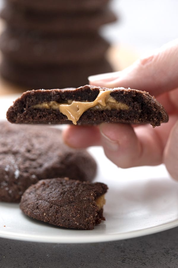 A keto chocolate cookie broken open to show the creamy peanut butter filling. 