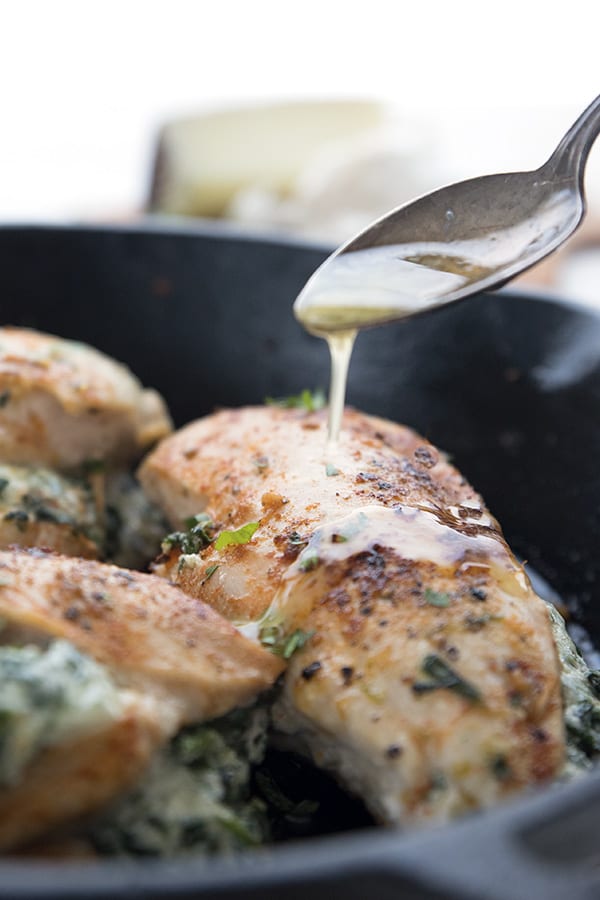 Drizzling garlic butter over spinach stuffed chicken breast.