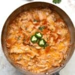 Top down image of Keto Enchilada Skillet in a metal pan, with jalapeño and cilantro above it.