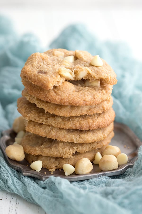 A stack of chew keto cookies on a pewter plate with a gauzy teal napkin