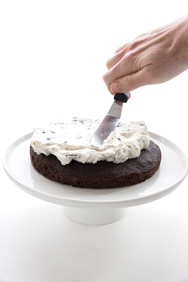 Spreading low carb cookies and cream frosting on a keto chocolate cake.