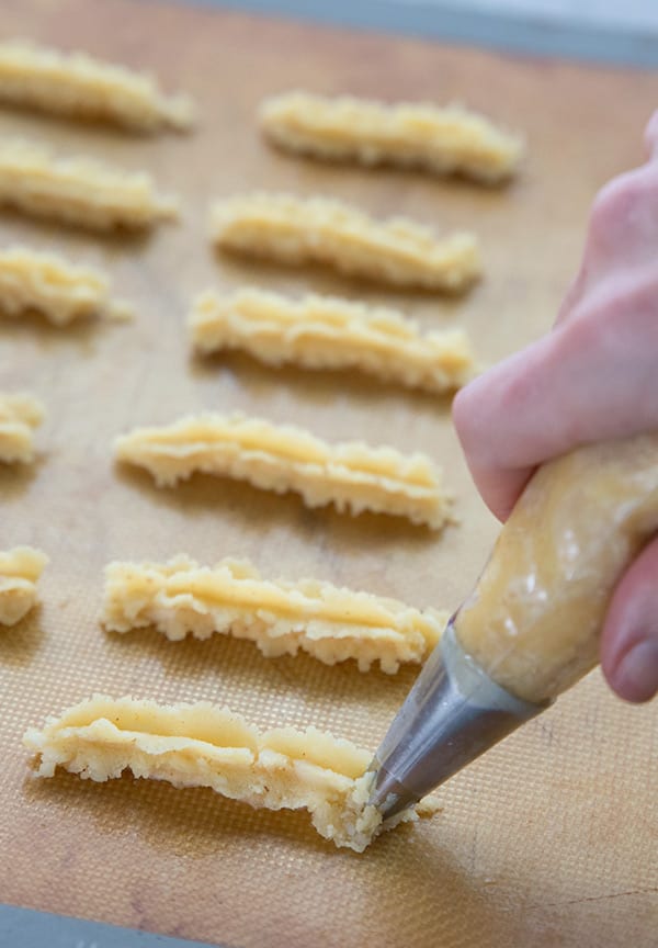 Piping cheese straw dough onto a baking sheet. 