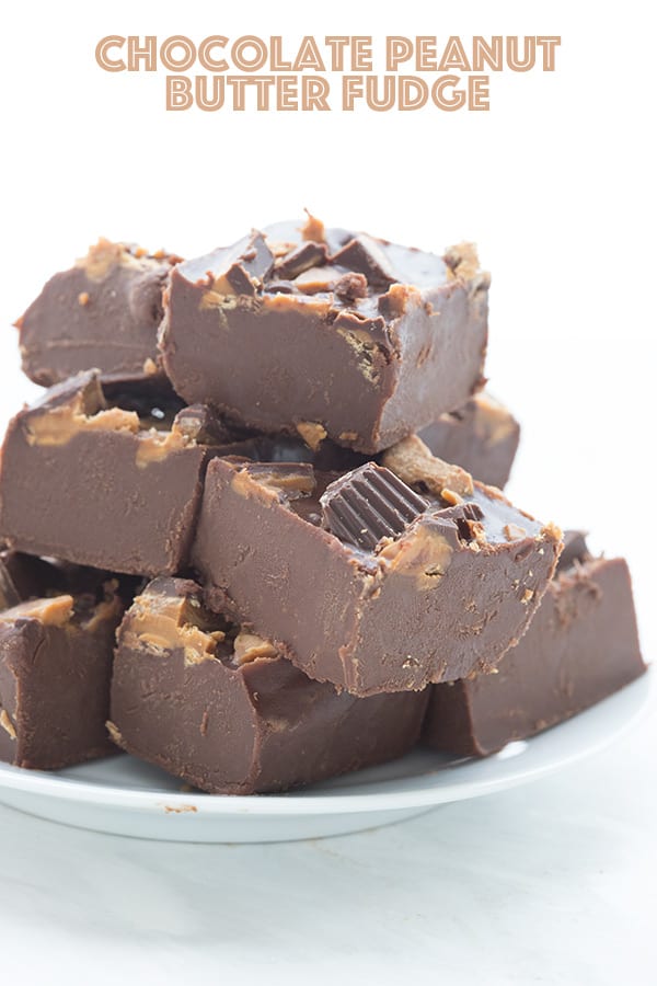 Easy keto fudge cut into pieces on a white plate. Sugar-free peanut butter cups are pressed into the top of the fudge. 