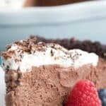 Close up shot of a slice of Keto Chocolate Mousse Pie on a white plate with berries.