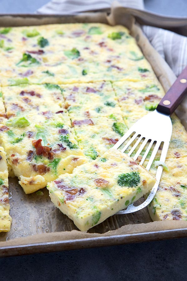 Sheet pan frittata wth bacon, broccoli and cheese, cut into slices on the sheet pan. 