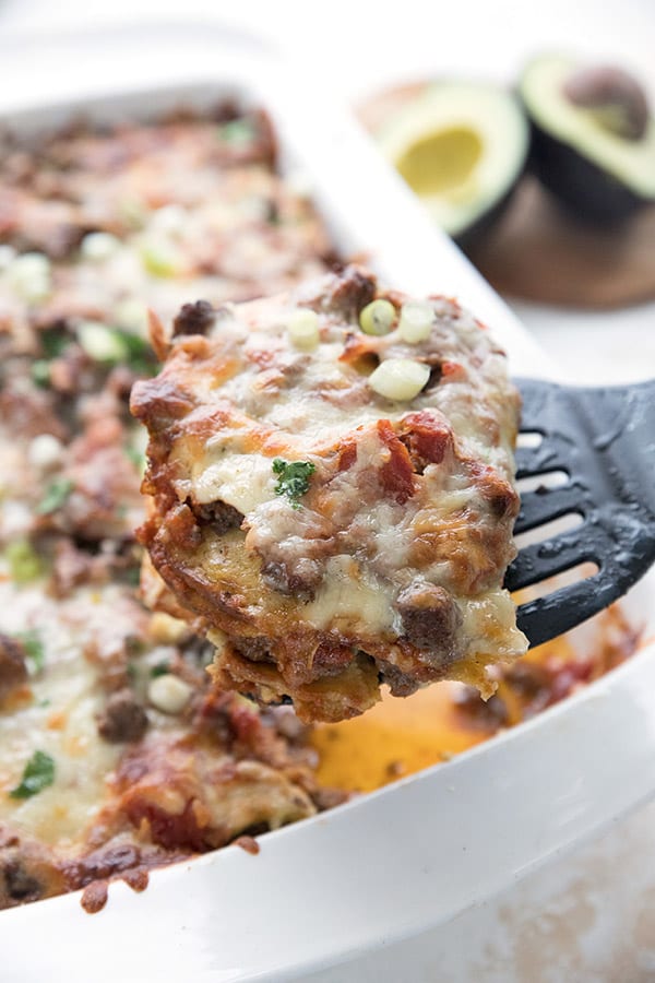 Close up of a slice of keto enchilada casserole being lifted out of the pan. 