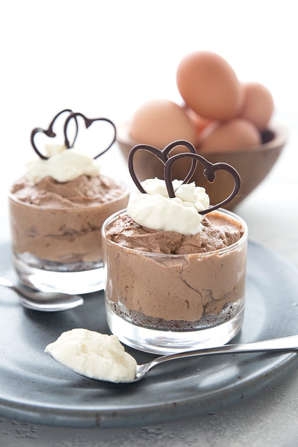 Two mini french silk pies with a bowl of eggs in the background. 