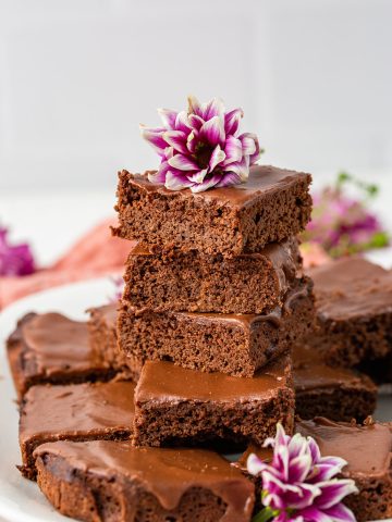 A plate piled high with coconut brownies, with flowers around it.