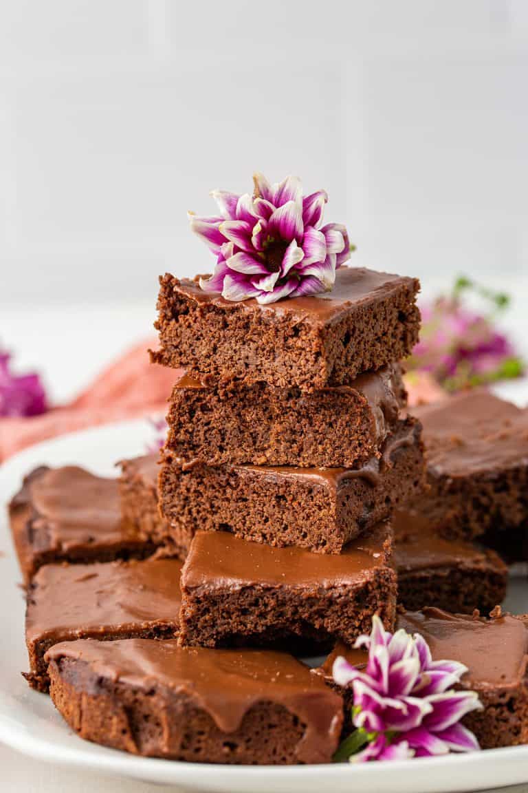 A plate piled high with coconut brownies, with flowers around it.