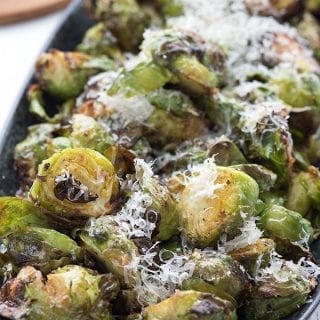 Close up shot of keto garlic parmesan Brussels sprouts in a black serving dish.