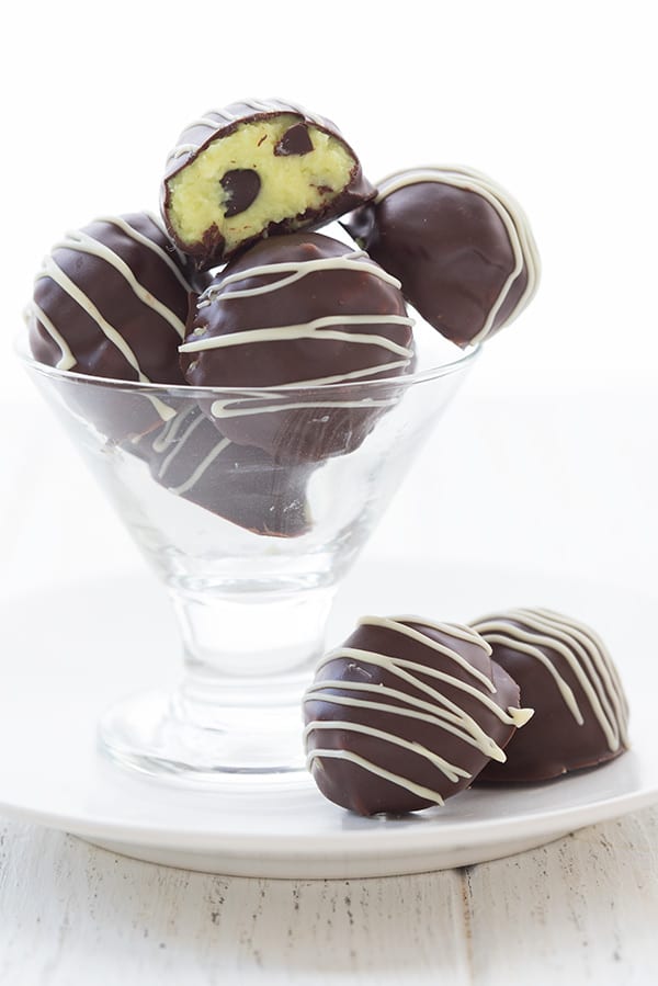 Mint chocolate chip truffles piled in a dessert glass, with two truffles in front. 
