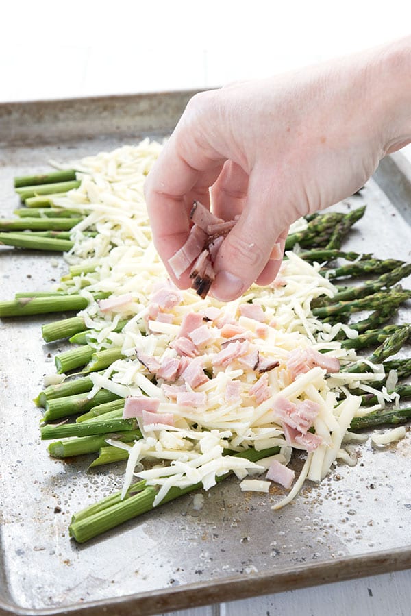 Sprinkling chopped ham over baked asparagus