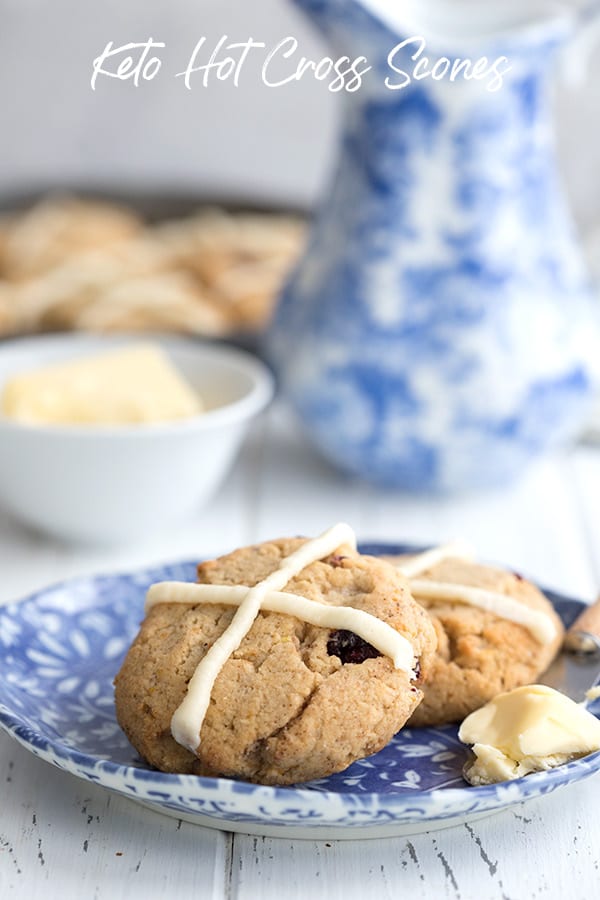 Hot cross scones on a blue patterned plate with a smear of butter. 