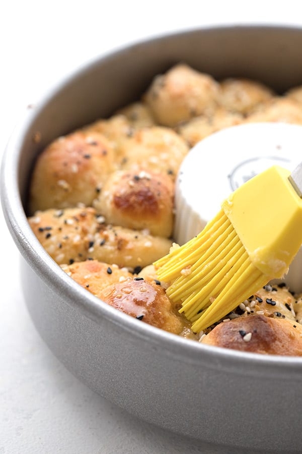 Close up shot of a pastry brush brushing butter over keto everything bagel bread.