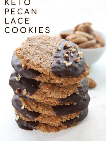 A stack of chocolate dipped pecan lace cookies with a bowl of pecans in the background