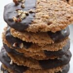 Titled image of a stack of Keto Pecan Lace Cookies dipped in chocolate, on a white background.