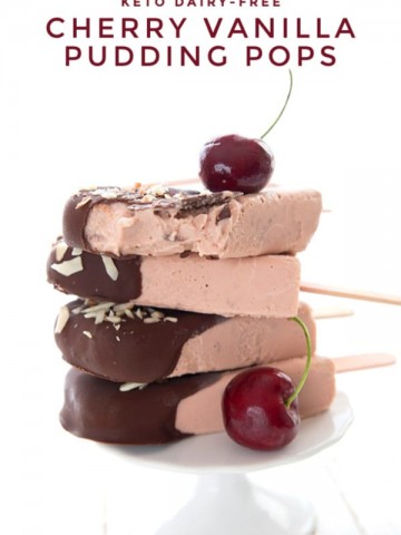 Titled image of Keto Cherry Popsicles in a stack on a white cake plate, with a cherry on top.