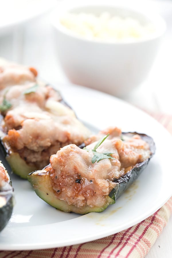 Close up shot of keto stuffed zucchini cut open to reveal the sausage and cheese stuffing.