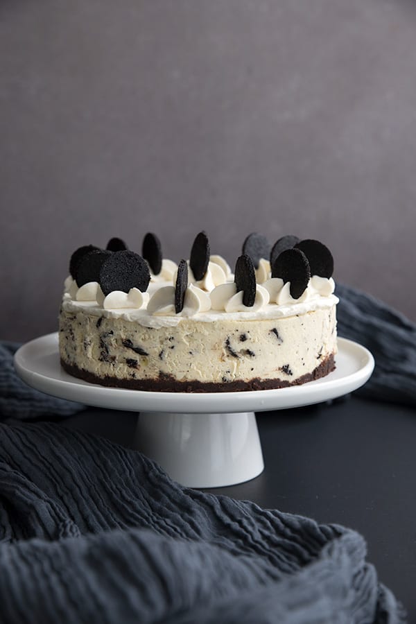 Keto Instant Pot "Oreo" Cheesecake on a white cake plate on a grey background.