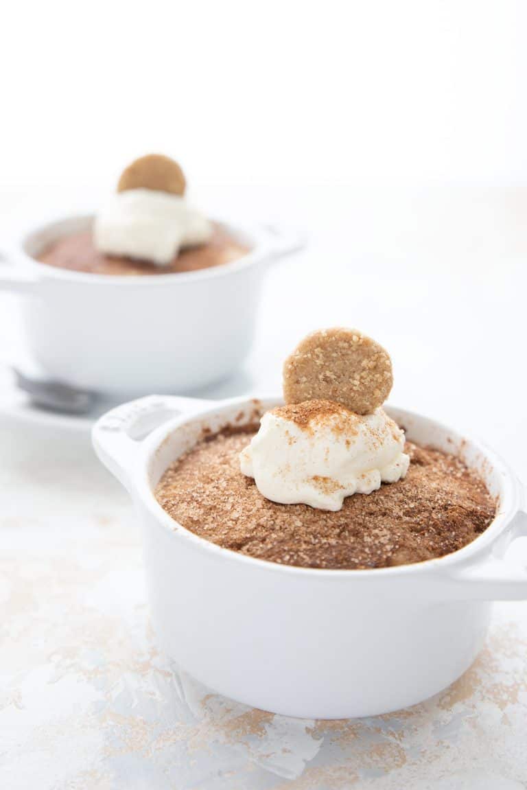 Two cinnamon keto mug cakes in white ramekins on a white table.