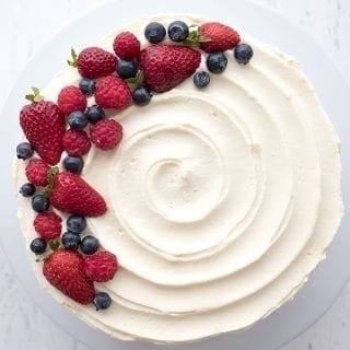 Top down photo of Berry Chantilly Cake with swirls in the frosting and a garnish of fresh berries.