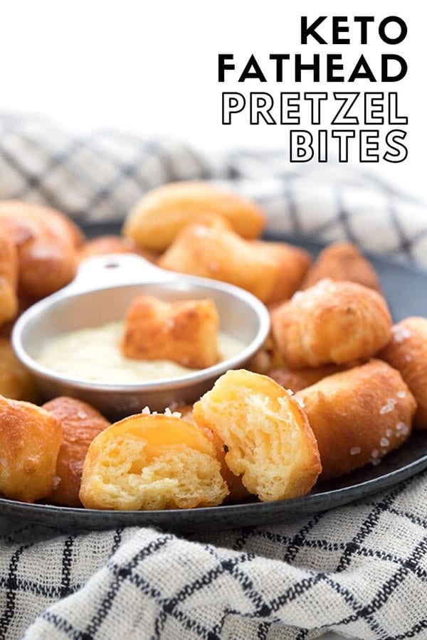 Titled image: a close up of keto pretzel bites on a black plate over a checked napkin. The front bite is broken open to show the inside.