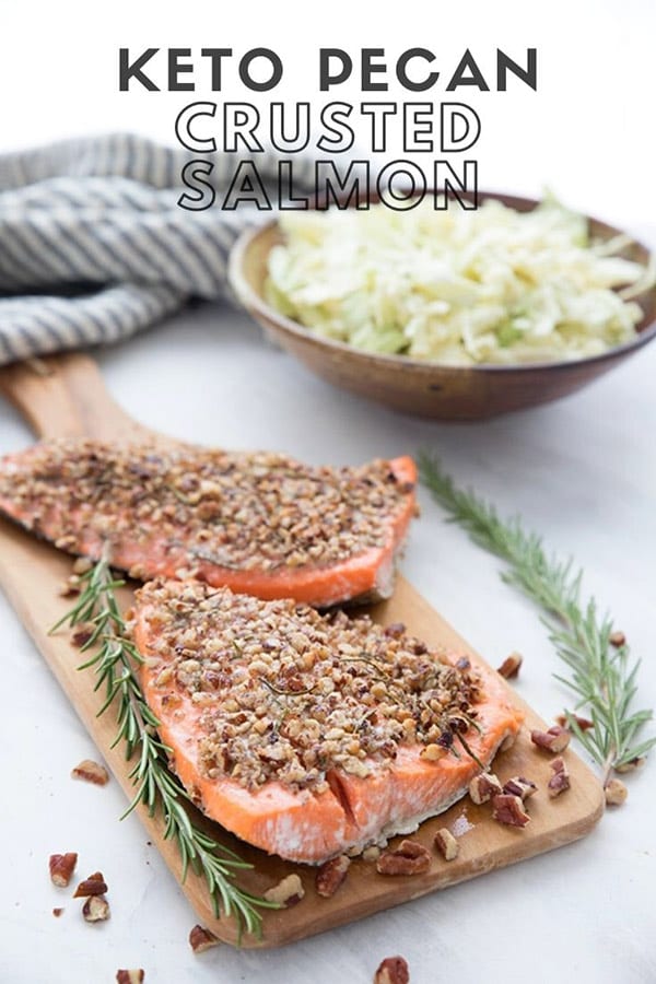 Titled Image: Keto Pecan Crusted Salmon with two pieces of salmon on a cutting board and a bowl of coleslaw in the background.
