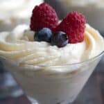 Titled image of a small dessert glass filled with Keto White Chocolate Mousse with berries on top.