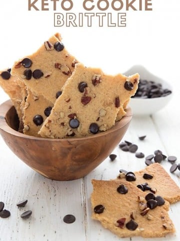 Titled image of keto cookie brittle in a wooden bowl on a white wooden table.