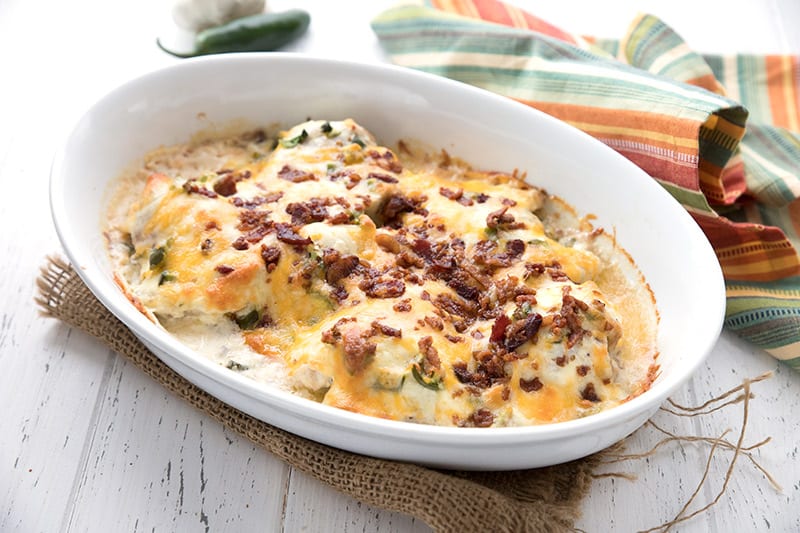 A white oval baking dish filled with jalapeno popper smothered chicken.