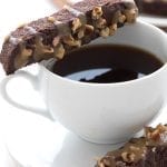 Close up shot of keto turtle biscotti balanced on a cup of coffee