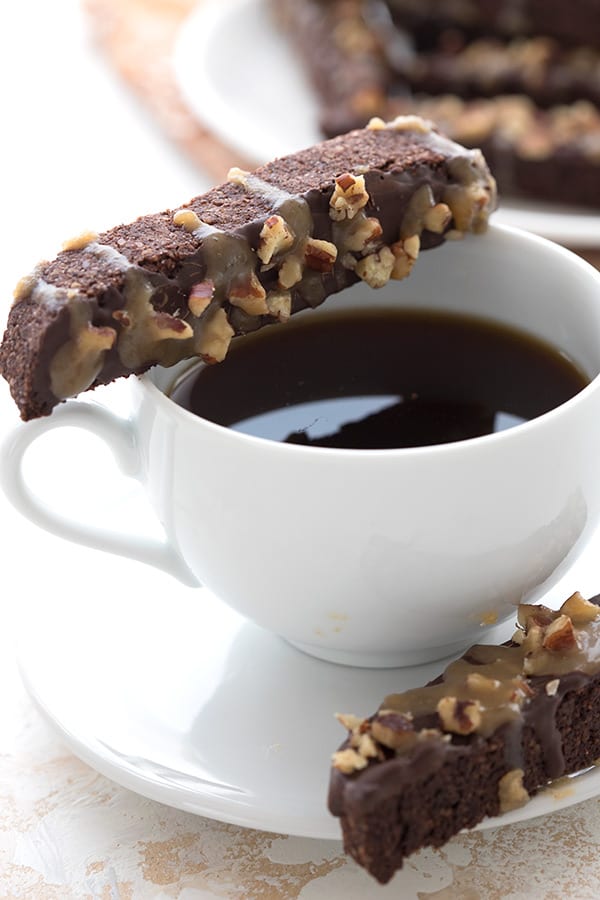 Close up shot of keto turtle biscotti balanced on a cup of coffee