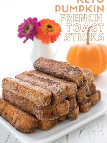 Titled image of keto french toast sticks on a white plate, with a pumpkin and some flowers in the background.