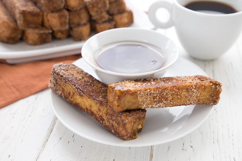Two keto french toast sticks on a white plate with keto syrup
