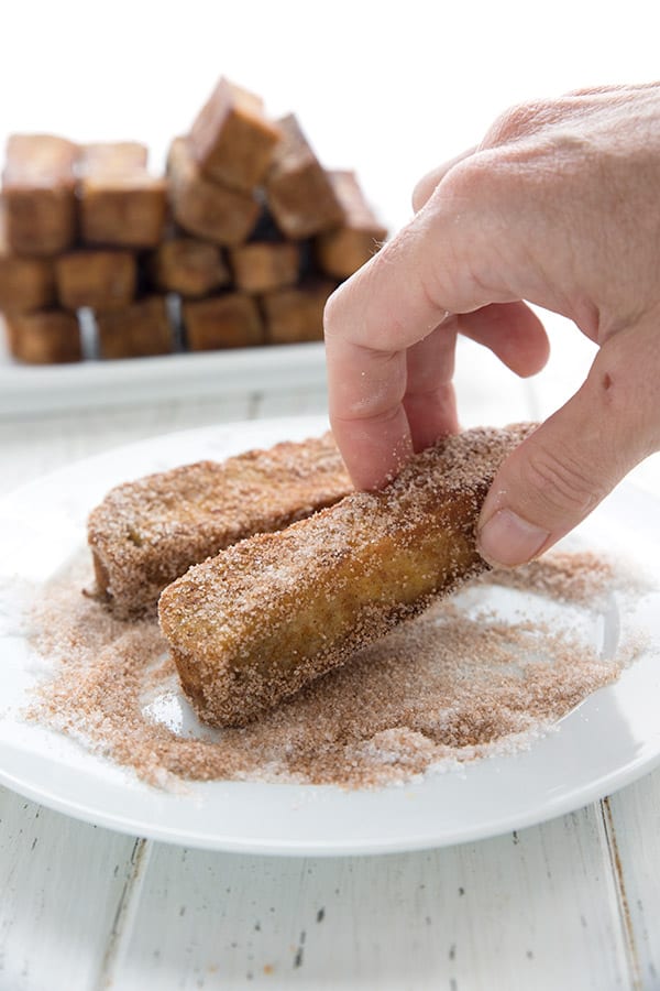 Rolling keto pumpkin french toast sticks in cinnamon and sweetener