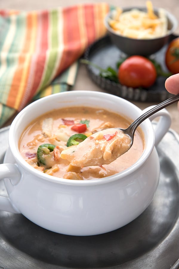 A spoon digging into slow cooker King Ranch Chicken Soup