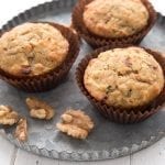 Three keto morning glory muffins on a metal plate with walnuts.