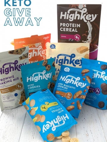 A collection of HighKey keto snacks, cookies, and cereals on a white wooden table.