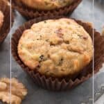 Close up shot of two keto morning glory muffins in brown paper liners on a metal dish.