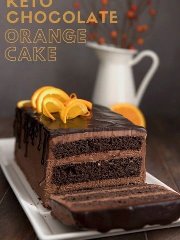 Titled image of keto chocolate orange layer cake on a white platter, with one slice cut out.