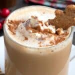 Titled image of a Keto Gingerbread Latte on a white plate with a small keto gingerbread cookie on top.