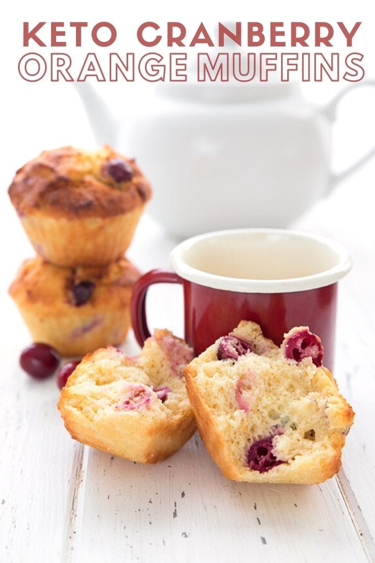 Titled image of keto cranberry orange muffins on a white table with a red cup of coffee. The muffin in front is broken up to show the inside.