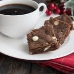 Three keto gingerbread white chocolate blondies on a white plate over a red plaid napkin