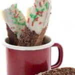 Titled image of keto gingerbread biscotti in a red mug, with one sitting in front.