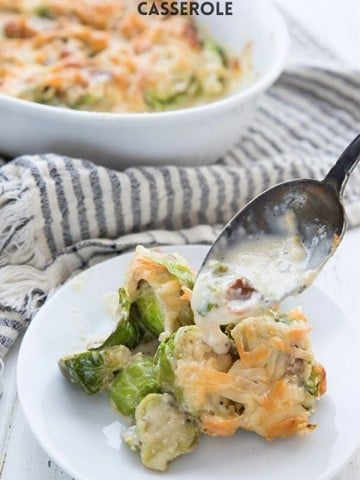 Titled image for Brussels Sprouts Casserole, with a spoon dishing some of the creamy sauce over the plate.